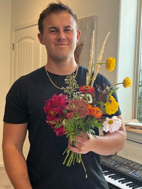 young man holding a bouquet he made
