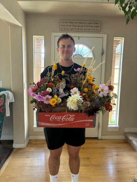 young man is holding a coca cola crate full of colorful flower bouquets